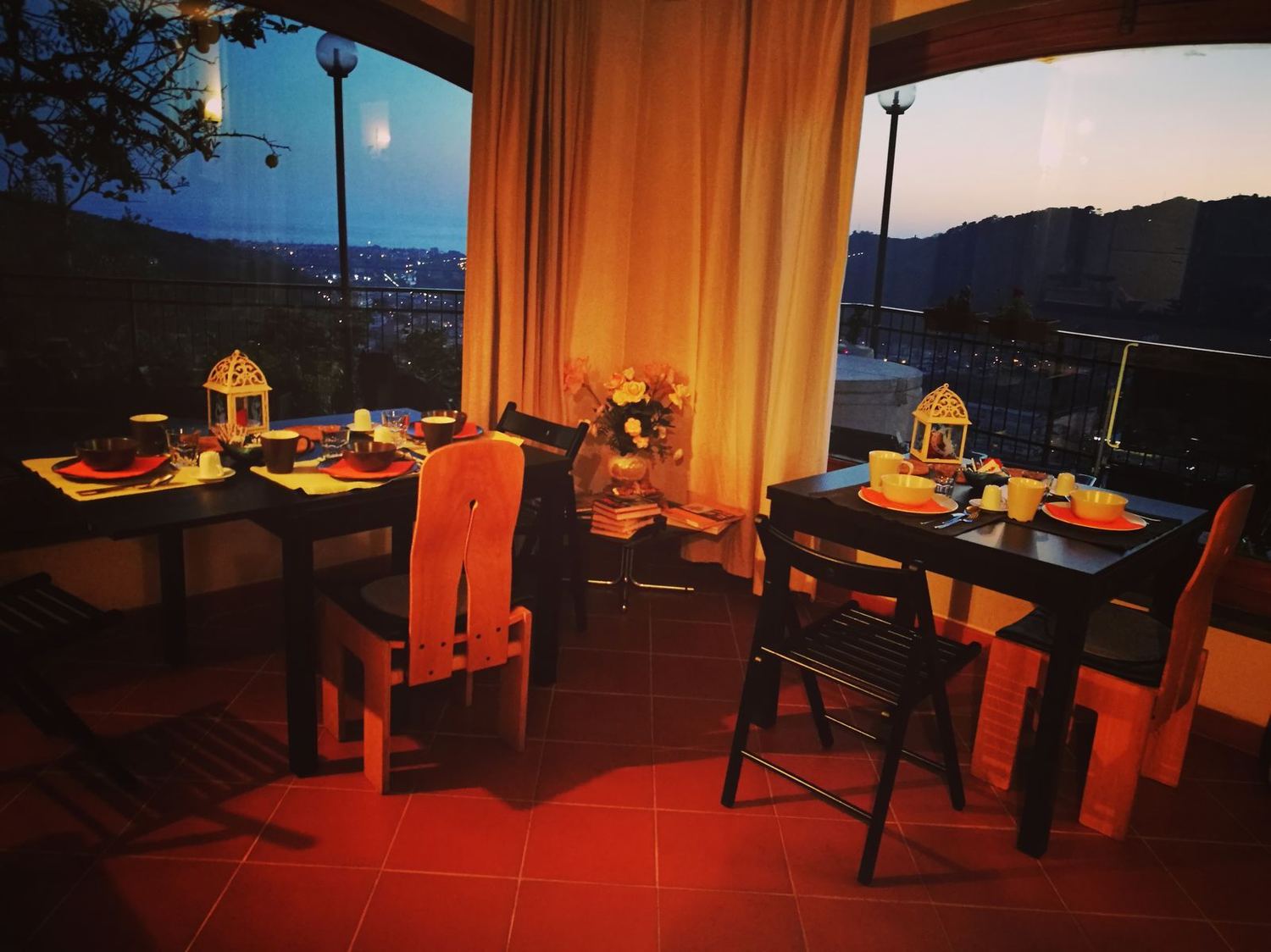 The breakfast room at sunset, tables laid and the view over the coast
