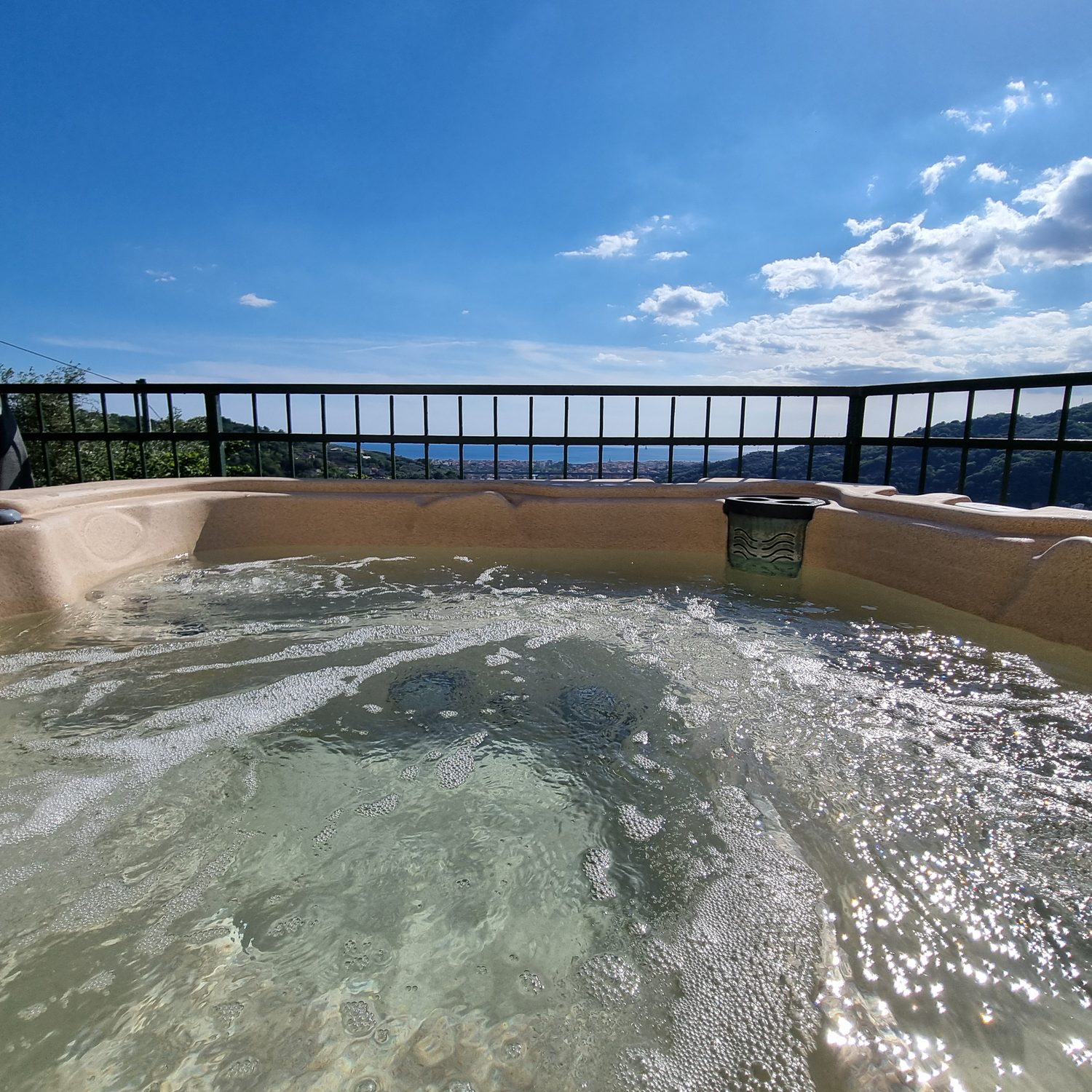La vasca idromassaggio in terrazza vista da vicino, con l'acqua che bolle e il golfo del Tigullio dietro la ringhiera